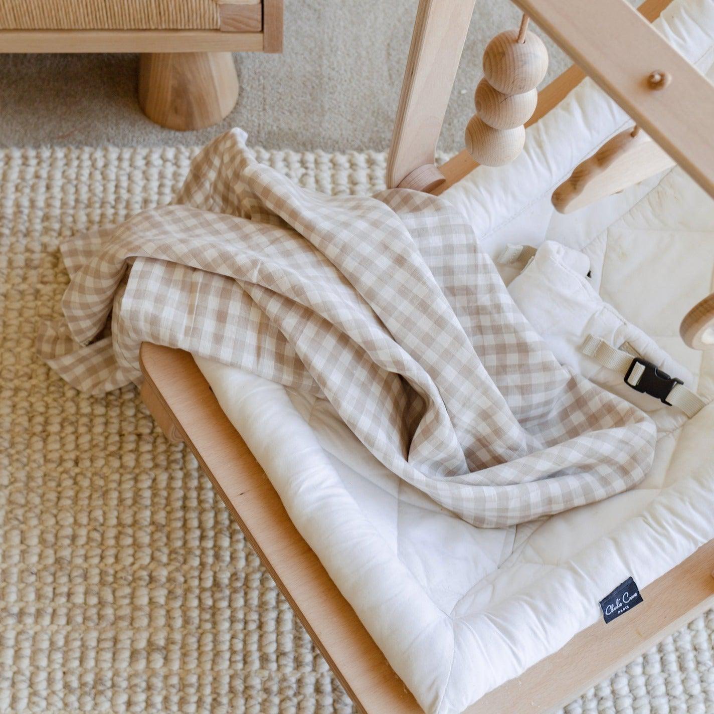 A Warren Hill french linen baby swaddle draped with a cozy blanket.