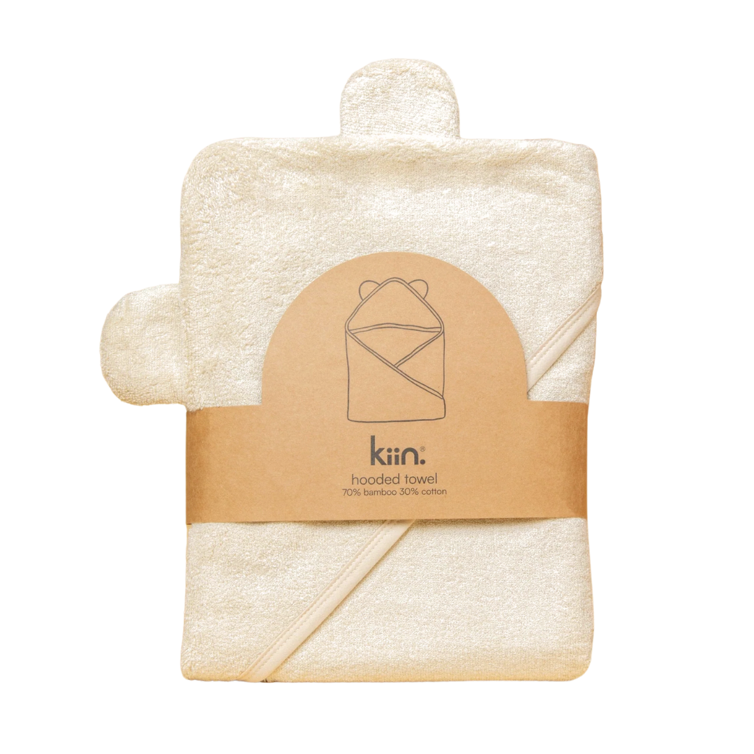 This charming hooded baby towel from Kiin, in a lovely ivory hue, boasts an endearing bear ear design and is made from a plush blend of cotton and bamboo. Wrapped with a brown label that reads "Kiin: hooded towel, 70% bamboo 30% cotton," it offers both comfort and style for your little one.