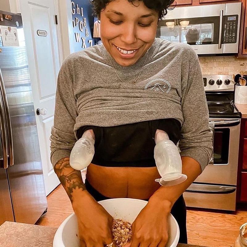 A woman preparing a bowl of food in a kitchen and using the Haakaa Silicone Breast Puvmp 100ml Gen 1 by Haakaa.