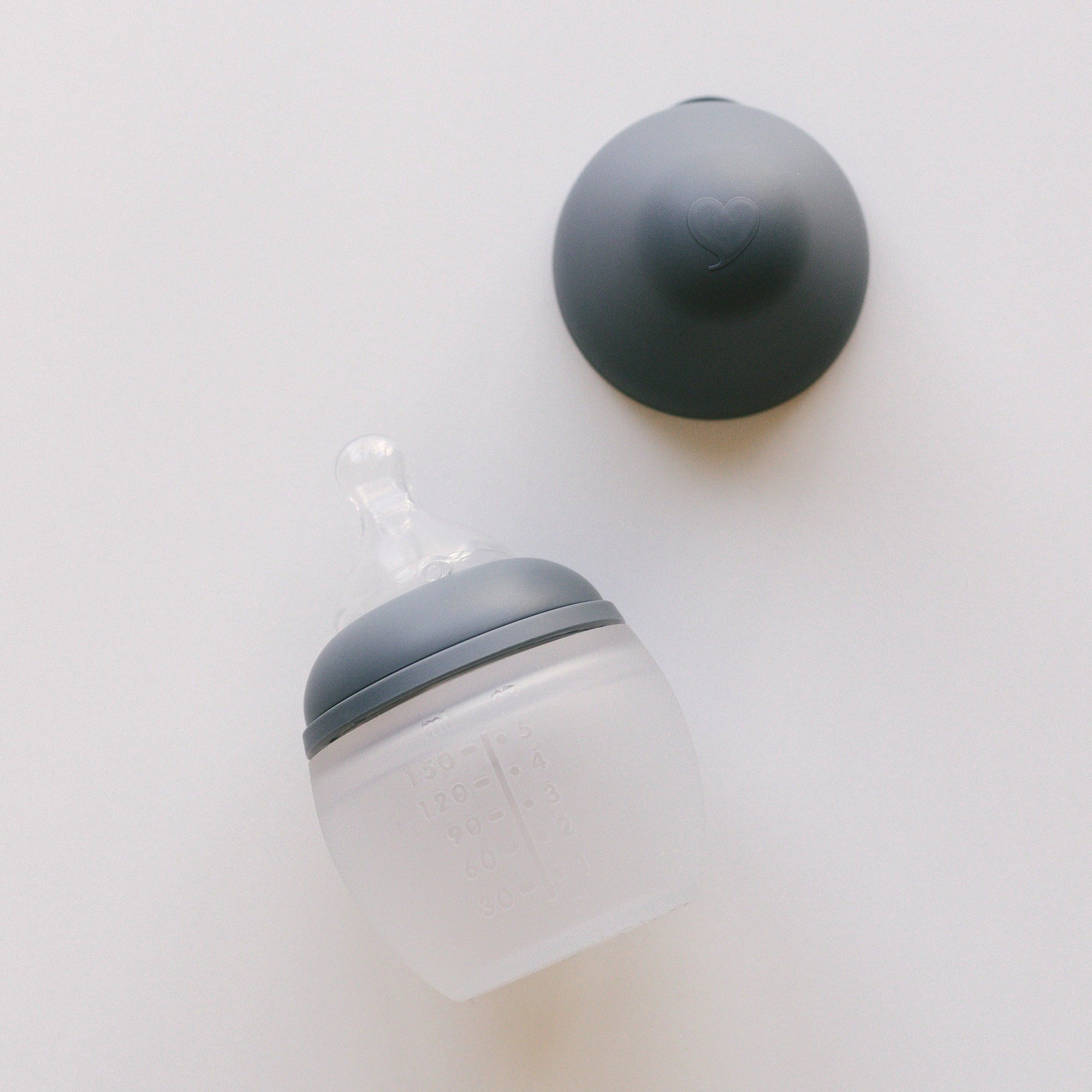 An Elhée France BibRond | blue grey baby bottle on a white surface.